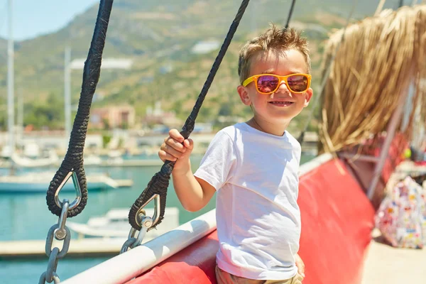 Engraçado menino posando em barco de excursão perto de belas montanhas — Fotografia de Stock