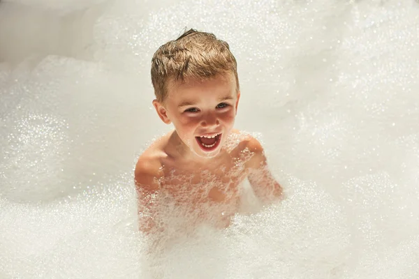 Menino feliz brincando no banho de espuma — Fotografia de Stock