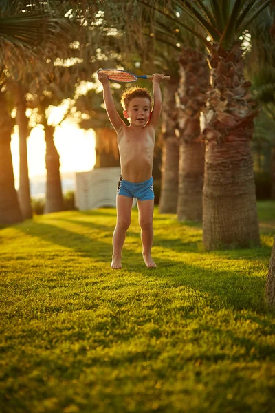 Menino bonito em troncos de natação pulando ao longo do beco da palma — Fotografia de Stock
