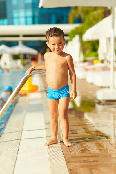 Bonito menino posando perto da piscina exterior — Fotografia de Stock