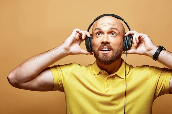 Jovem surpreendido sexy careca barbudo homem com fones de ouvido no fundo amarelo — Fotografia de Stock