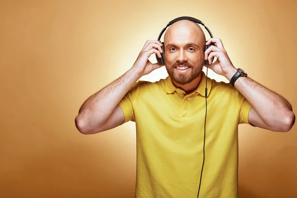 Jovem sorridente atraente em camiseta amarela com fones de ouvido — Fotografia de Stock