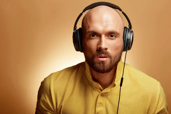 Bonito jovem careca no fundo amarelo e fones de ouvido — Fotografia de Stock