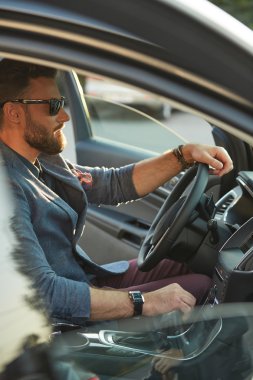 Ciddi sakallı yakışıklı bir araba kullanıyor