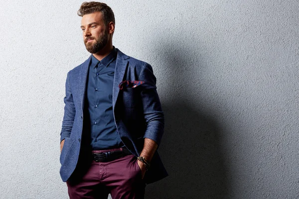 Handsome man standing near grey wall in business suit — Stock Photo, Image