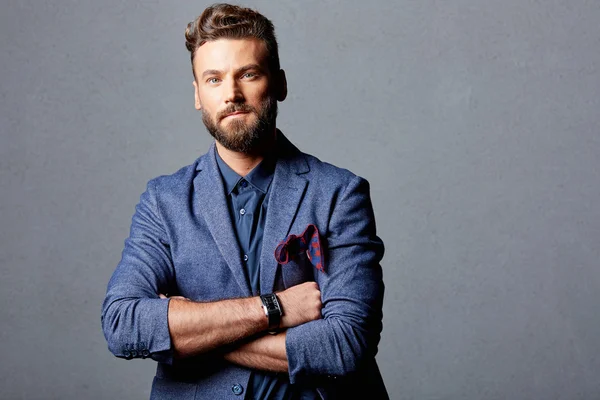 Handsome bearded man standing near grey wall — Stock Photo, Image