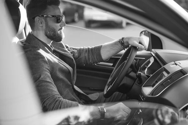 Handsome serious bearded man drives a car in black and white — Stock Photo, Image