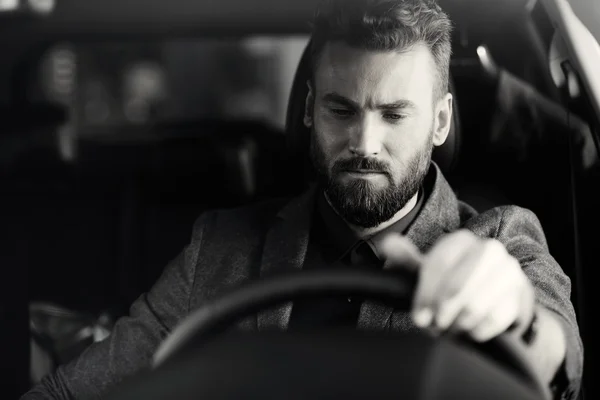 Handsome elegant serious man drives good car in black and white — Stock Photo, Image