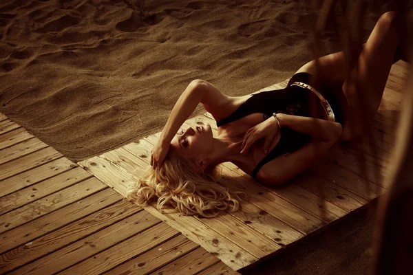 Приваблива блондинка в купальнику лежить на пляжі — стокове фото
