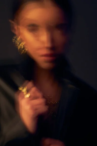 portrait with double exposure of a dark-eyed beautiful girl with black hair, professional make-up, dressed in a black jacket, she has gold jewelry on her arm and ears