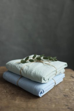 2 doğal ve ekolojik fotoğrafın yıkanmış pamuk kumaşları nane ve mavi renklerle geri sarılmış, üzerinde çuval iplik ve yeşil bitki var.