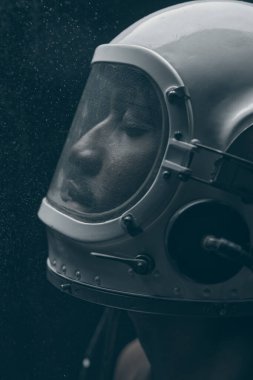 Siyah beyaz astronot kasklı koyu tenli bir adamın fotoğrafı. Gözleri kapalı olan adam.