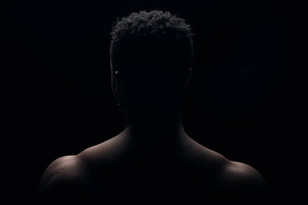一个年轻的黑人男子的黑色肖像 照片从后面黑暗的背景上拍摄 — 图库照片