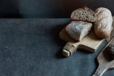 Taze ekmek ve ahşap kalaslarla siyah bir zemin üzerinde kompozisyon