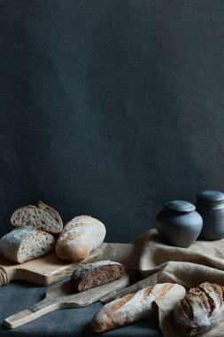 Siyah arka planda dikey, natürmort fotoğraf. Fotoğraf farklı ekmek ve siyah sürahileri gösteriyor.