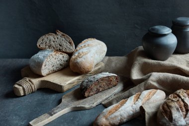 Siyah arka planda yatay natürmort fotoğrafı. Fotoğraf farklı ekmek ve siyah sürahileri gösteriyor.