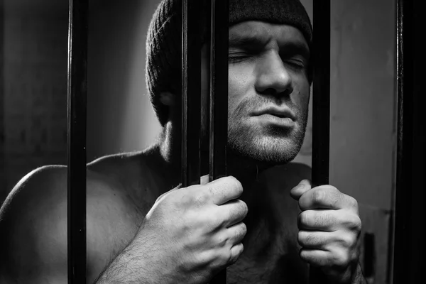 The prisoner worries about a criminal conduct being behind a lattice — Stock Photo, Image