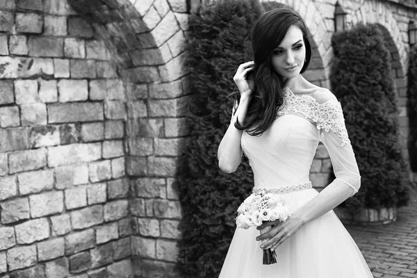 Die schöne junge Frau posiert in einem Hochzeitskleid — Stockfoto