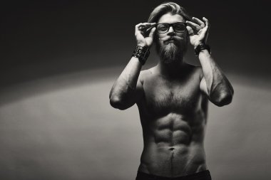 Çıplak göğüslü gri duvardan poz ile acımasız sakallı adam.