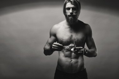 Çıplak göğüslü gri duvardan poz ile acımasız sakallı adam.
