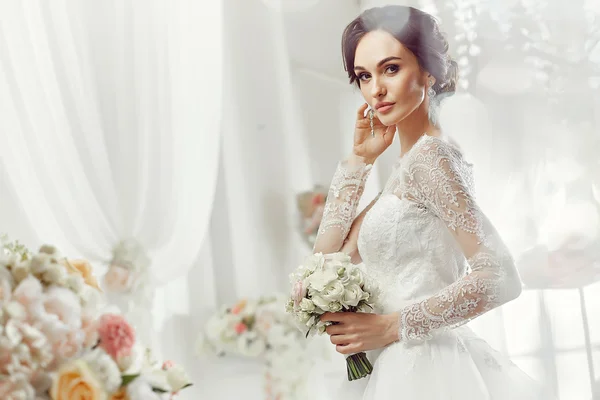 The beautiful woman posing in a wedding dress — Stok fotoğraf