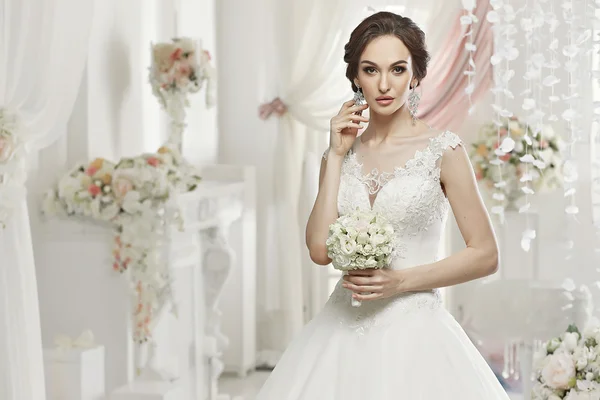 The beautiful woman posing in a wedding dress — Stok fotoğraf