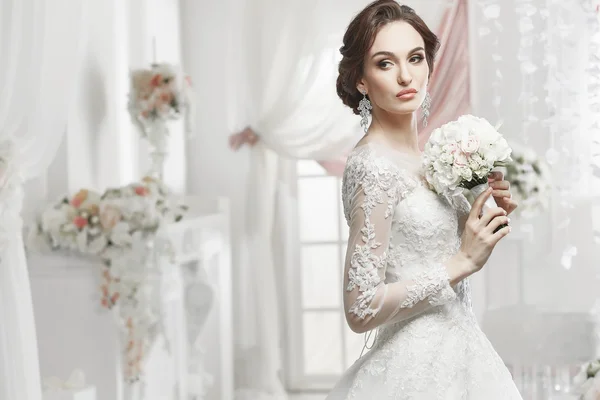 The beautiful woman posing in a wedding dress — Stock Photo, Image