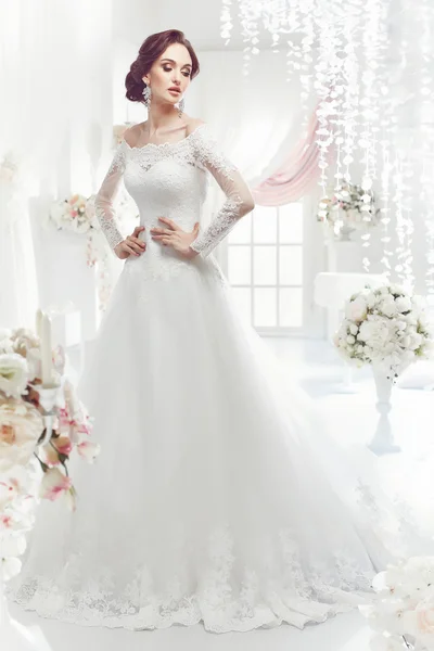 Den vackra kvinnan som poserar i ett bröllopsklänning — Stockfoto
