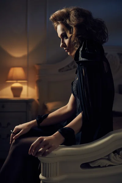 Vacker sexig Glamour brunett kvinna ligger i sängen i sovrummet i sensuella svart transparent Peignoir (underkläder). Lyxiga eleganta inredning med blått ljus. Natten eller kvällen — Stockfoto