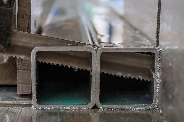 Řezání ocelových profilů na pásové pily ve výrobě. — Stock fotografie