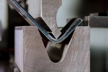 Fabrikadaki hidrolik bir makinede metal bükme levhası. Aletleri bük, frene bas, bas ve öl. Yakın plan..