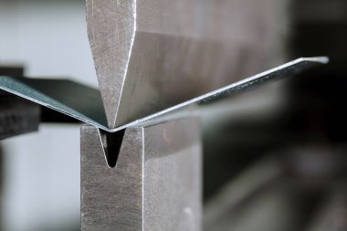 The process of bending sheet metal on a hydraulic bending machine clipart