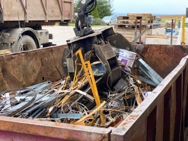 Hurda metali bir kamyona yüklüyorum. Turna yakalayıcısı rıhtımdaki paslı hurdaları yüklüyor. Yakalayıcı bir kamyon geri dönüşüm için endüstriyel metali yüklüyor.
