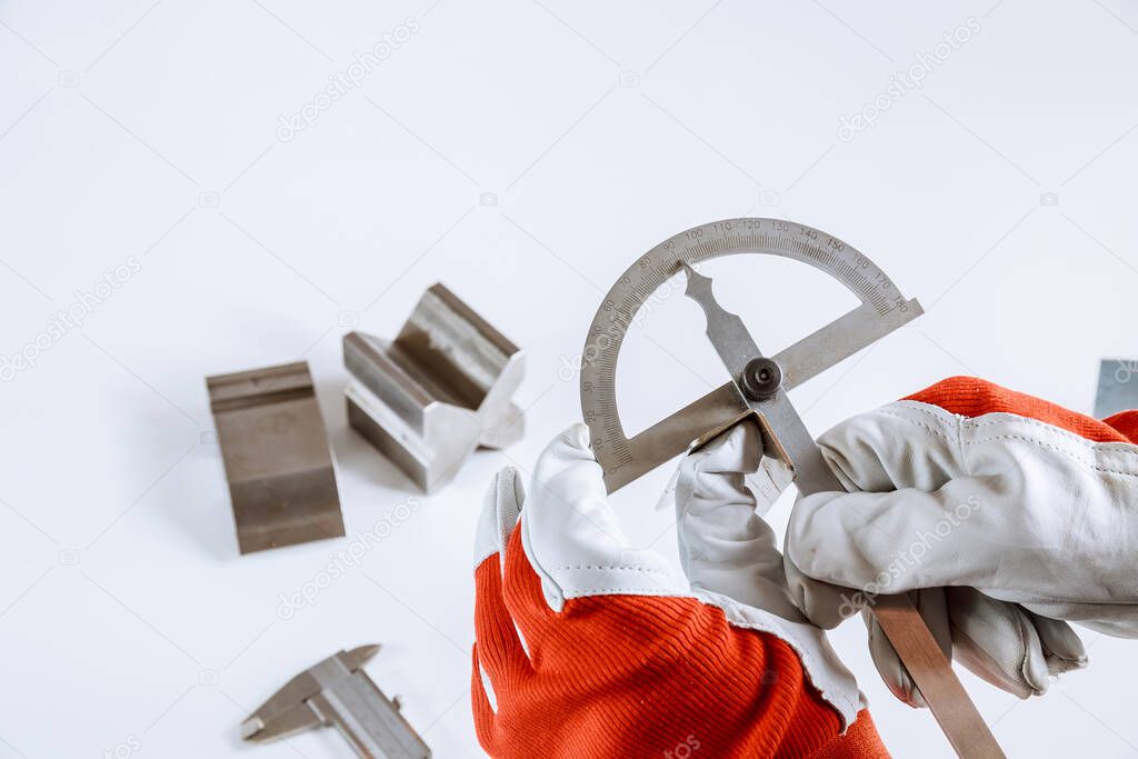 The worker measures the angle on the metal product with a protractor. Sheet metal bending tool and equipment on a white background.