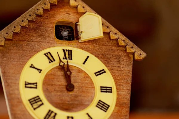 Clock face retro clock with cuckoo with roman numerals. It will soon be 12 oclock on the clock face. Close up.