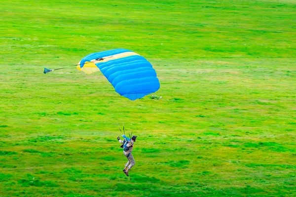 Een Parachutist Met Een Geel Blauwe Parachutescherm Landt Het Gras — Stockfoto