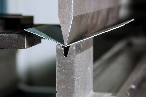 The process of bending sheet metal on a hydraulic bending machine. Metalworking plant.