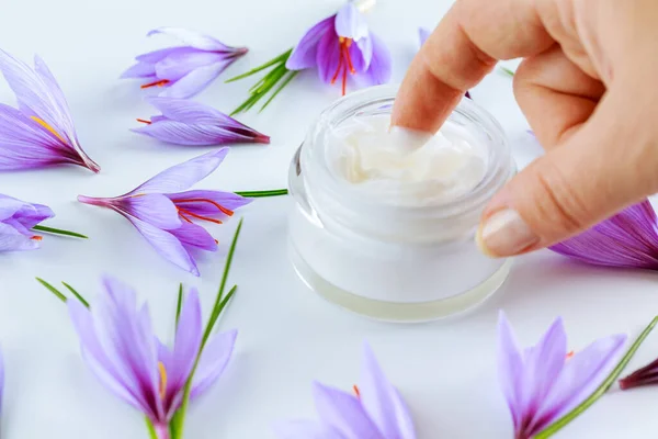 Saffron flowers on a white background and cosmetic cream with saffron extracts.