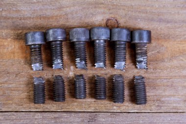 Ahşap arka planda kırılmış siyah cıvata. Sert cıvata.