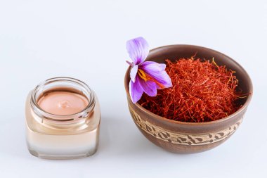 Mor crocus çiçeği, seramik bir kasede safran stamens ve beyaz arka planda kozmetik krem..