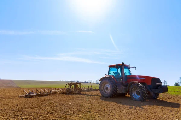 Seorang petani membajak tanah di ladang dengan bajak pahat di atas traktor. Traktor pertanian dengan bajak di lahan pertanian. — Stok Foto