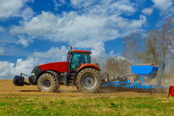 Een boer met een zaaimachine op een tractor - zaait graan in een landbouwveld. Tarwe verbouwen. — Stockfoto