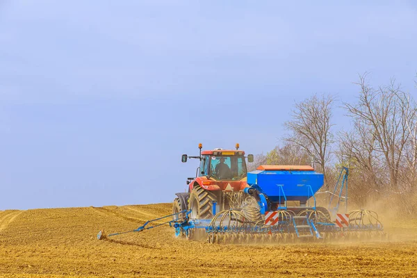 Um agricultor com uma semeadora em um trator - semeando grãos em um campo agrícola. Cultivo de trigo. — Fotografia de Stock