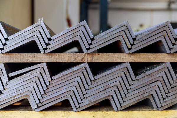 Rolled metal products, L-profile. A stack of angle steel in a factory. Metal profile after cutting with a band saw.