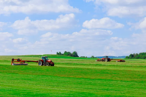 방앗간 주인 이 두 명인 거대 한 붉은 트랙터가해 초를 만들기 위해 잔디를 깎고 있다 — 스톡 사진