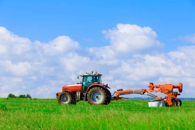 İki çim biçme makineli büyük kırmızı traktör çimleri biçer.
