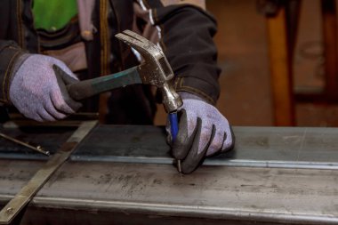 İşçi, demir sütuna delik açmadan önce orta yumrukla işaret koyar..