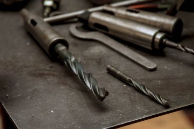 Masadaki iplikleri kesmek için matkaplar falan. Çilingir işyeri karmaşası.