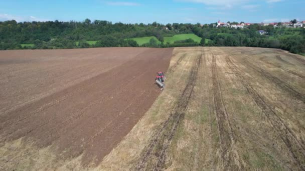 Red Tractor plowing a large field. Farmer on a tractor preparing the land for sowing. Top view. — Stock Video