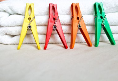 Beyaz arka planda iki adet kabarık banyo havlusu ve mandal yığını renkli plastik mandallar ve alttaki yazı için bir yer.